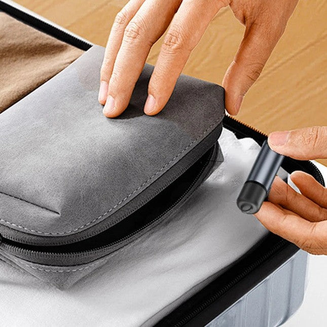 Hands packing a small grey pouch and a compact USB-C lighter into a travel case.